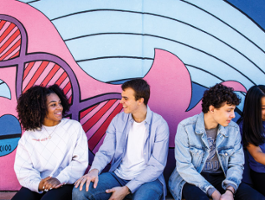 Four 博彩网址大全 students chatting in front of a painted mural